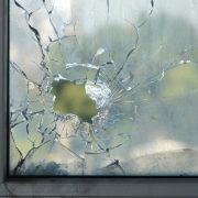 A closeup of a window with a large crack in it with a hole in the middle.