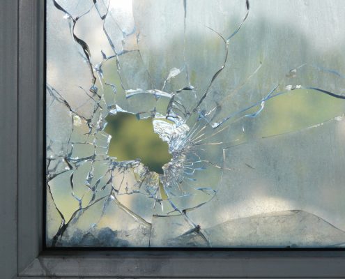A closeup of a window with a large crack in it with a hole in the middle.